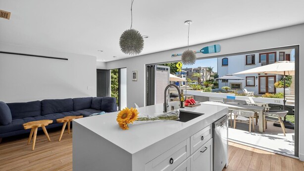 A modern kitchen with a central island, a dining area with outdoor seating, and a view of the neighborhood.