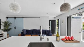 A modern kitchen with a white countertop, stainless steel sink, and a dining area with a table and chairs.