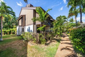 Un edificio moderno con techo plano, rodeado de abundante vegetación y palmeras.