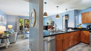 A modern kitchen with wooden cabinets, a stainless steel dishwasher, and pendant lights.