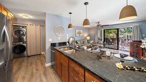 A modern kitchen with a built-in washer and dryer, a large island with a sink, and pendant lighting.