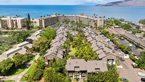 A coastal hotel with a central courtyard, multiple-story buildings, and a view of the ocean.