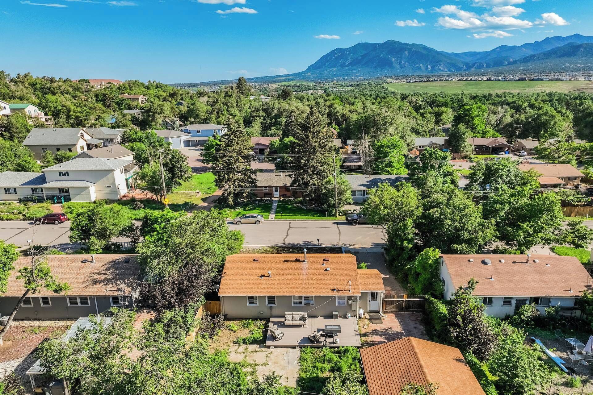 Un quartier résidentiel avec des maisons, une cour arrière équipée d’un barbecue et une montagne en arrière-plan.