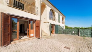 A two-story building with a paved courtyard, large wooden doors, and a metal gate.