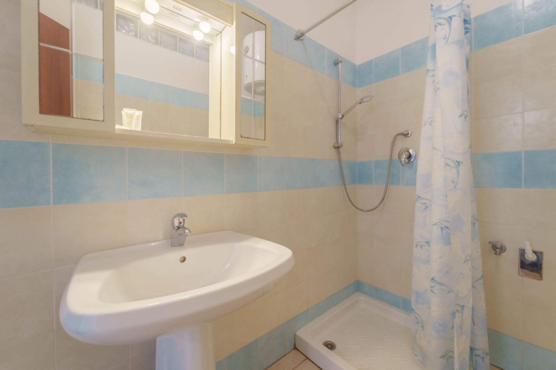 Un baño con lavabo, ducha y espejo.