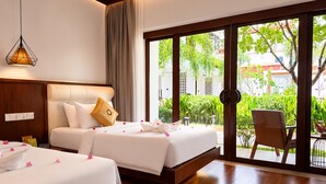 A hotel room with two beds, a large sliding glass door to a garden, and a hanging light fixture. - Happy Resort Siem Reap (Siem Reap)