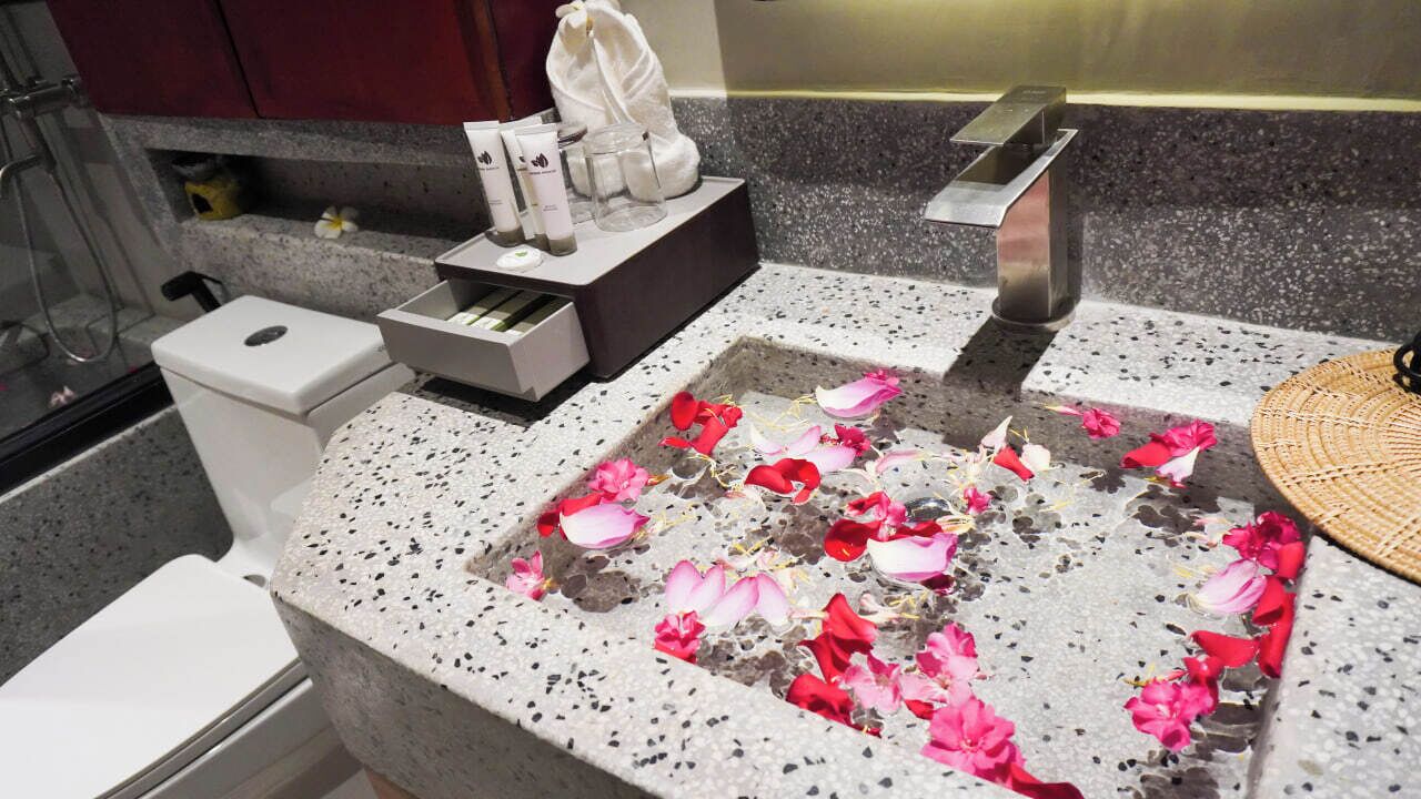 A bathroom with a granite countertop, a white sink, a towel rack, and a shower area.