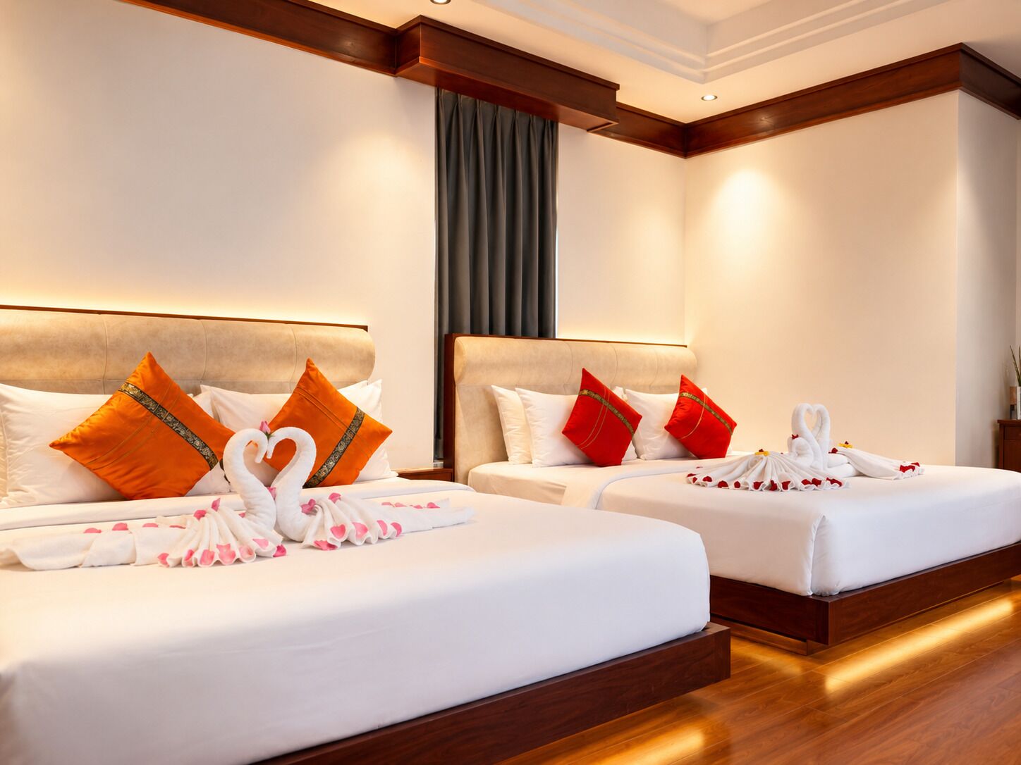 A hotel room with two beds, each with a headboard, pillows, and a towel arrangement.