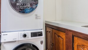 Lavadora y secadora apiladas en una cocina con gabinetes de madera.