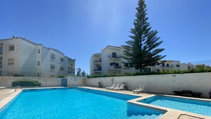 A swimming pool with clear blue water, surrounded by a low wall and a few lounge chairs. - Rustic and peaceful with pool (Lagos)