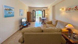 A living room with a sofa, a TV, and a dining area with a table and chairs. - Rustic and peaceful with pool (Lagos)