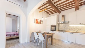 Una cocina moderna con armarios blancos, una mesa de comedor de madera y una lámpara colgante.