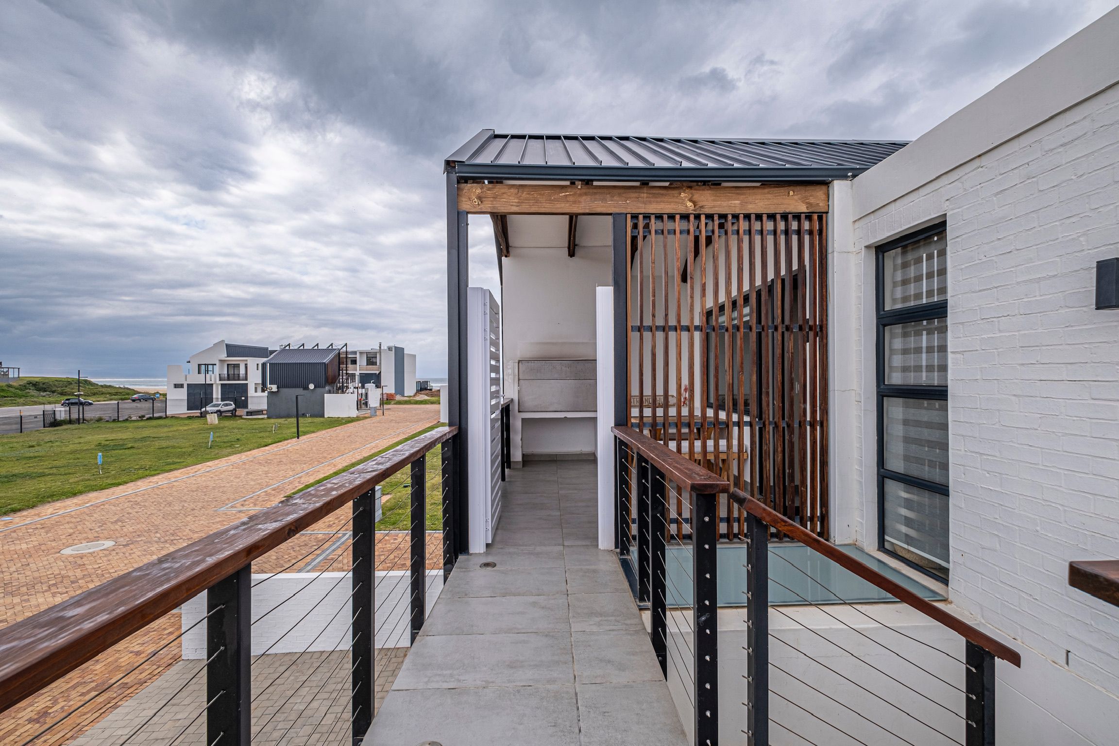 Un bâtiment moderne doté d’un espace extérieur couvert, d’une rambarde en métal et offrant une vue sur la mer.