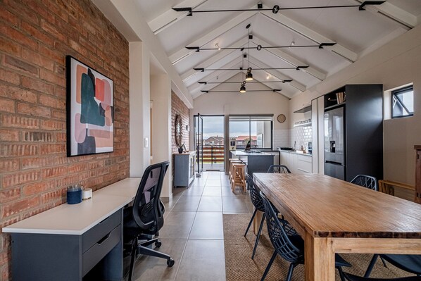 Una cocina moderna con pared de ladrillo, una mesa de comedor de madera y una isla de cocina.