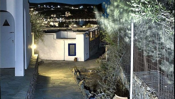 A nighttime view of a building with a moon in the sky, a stone pathway leading to the entrance, and a fenced garden area.
