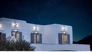 A modern building with three windows, each with shutters, under a starry night sky.