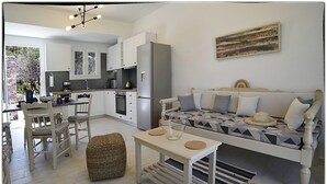 A modern kitchen with white cabinets and a dining area with a striped chair.