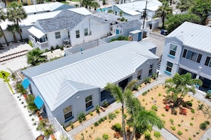 Zona residencial con varias casas, cada una con techo metálico inclinado y un pequeño jardín delantero con diversas plantas.