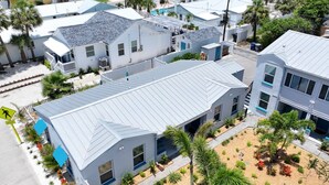 Zona residencial con varias casas, cada una con techo metálico inclinado y un pequeño jardín delantero con diversas plantas.