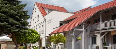 A building with a red-tiled roof, a staircase, and a sign that reads "Pension".