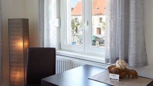 Ein Zimmer mit Blick auf eine Straße, ein Tisch mit einer Dekoration, ein Stuhl und eine hohe Lampe.