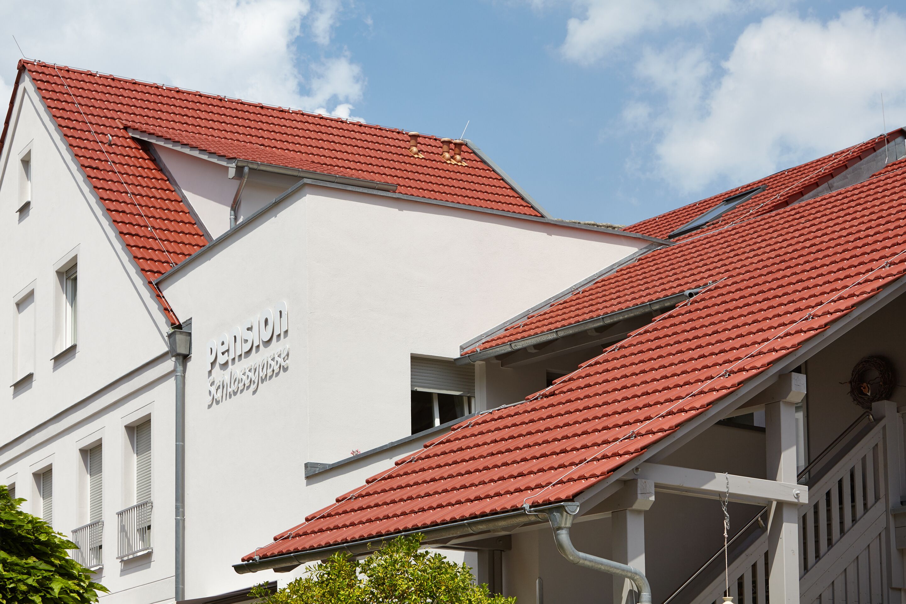 A building with a red-tiled roof and a sign that reads "Pension Schlosser".