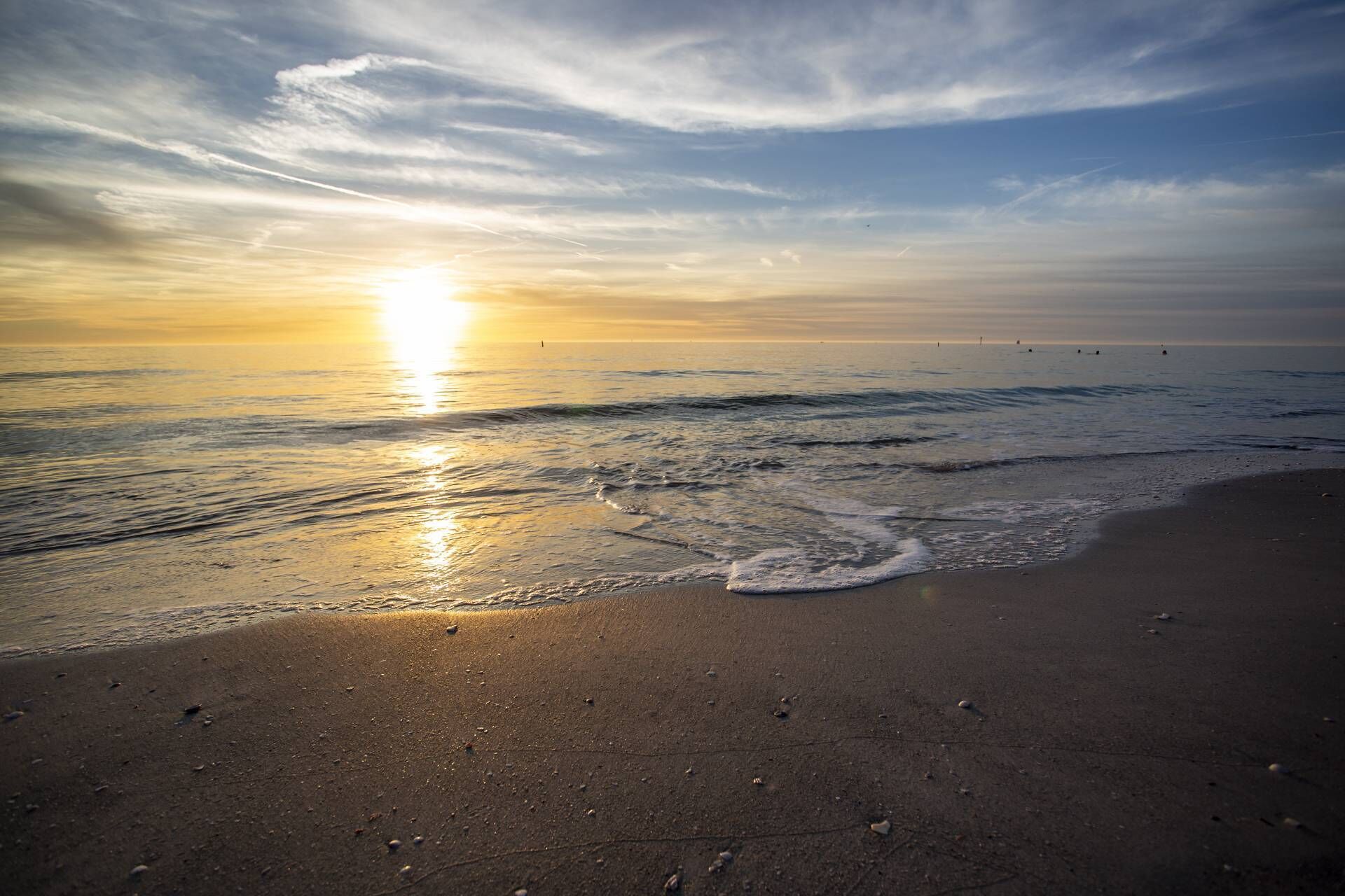 Ein Strand mit Wellen und einem Sonnenuntergang.