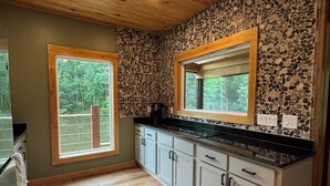 Eine Küche mit Holzschränken, einer Steinrückwand und zwei Fenstern.