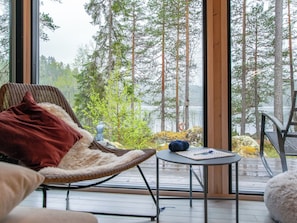 Et hyggeligt værelse med udsigt over en skov og en sø.