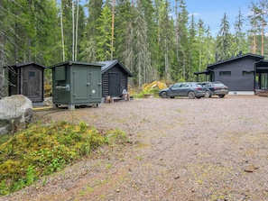 En grusparkering med to hytter og en bil.