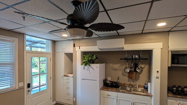 A modern kitchen with white cabinets, a built-in oven, and a ceiling fan.