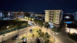 Een meerlaags gebouw met een modern ontwerp, omringd door een verlicht parkeerterrein en een aangelegde tuin.