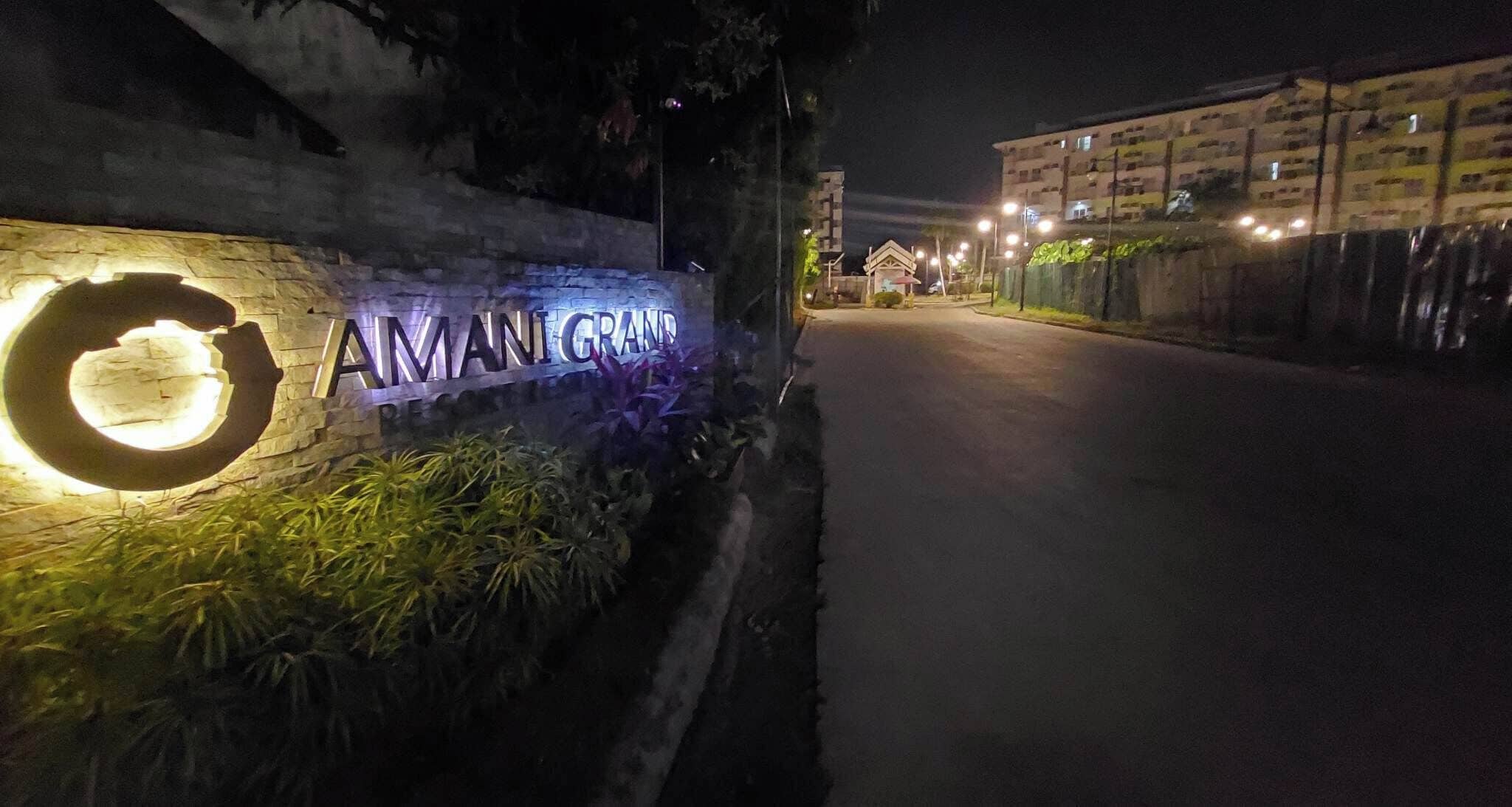 Une vue nocturne de l’entrée d’un immeuble, avec une enseigne sur laquelle on peut lire « AMANIGRAND ».