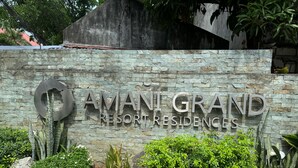 Naamplaatje voor 'AMANT GRAND RESORT RESIDENCES', met een stenen muur en beplanting.