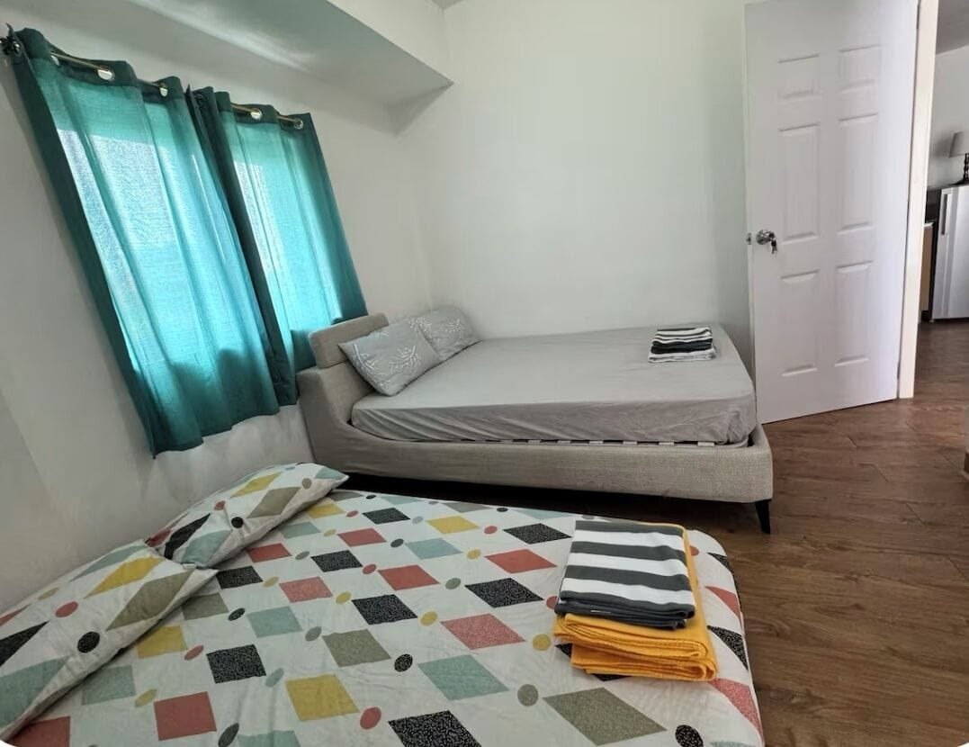 Una habitación pequeña y compacta con una cama, un sofá y una puerta que da a otra habitación.
