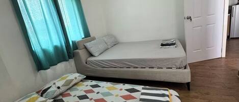Una habitación pequeña y compacta con una cama, un sofá y una puerta que da a otra habitación.