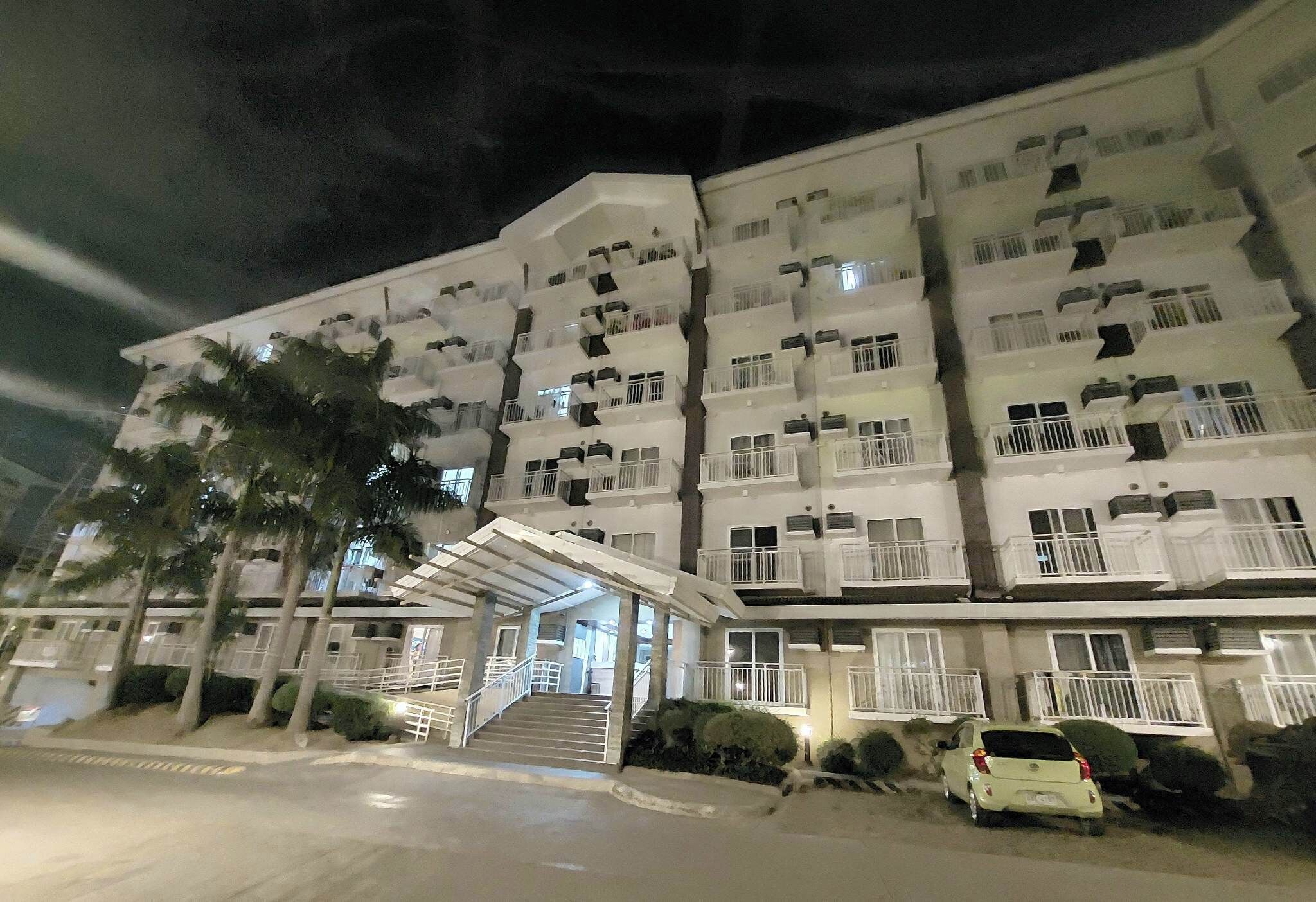 A multi-story hotel with balconies, a covered entrance, and a parking area.