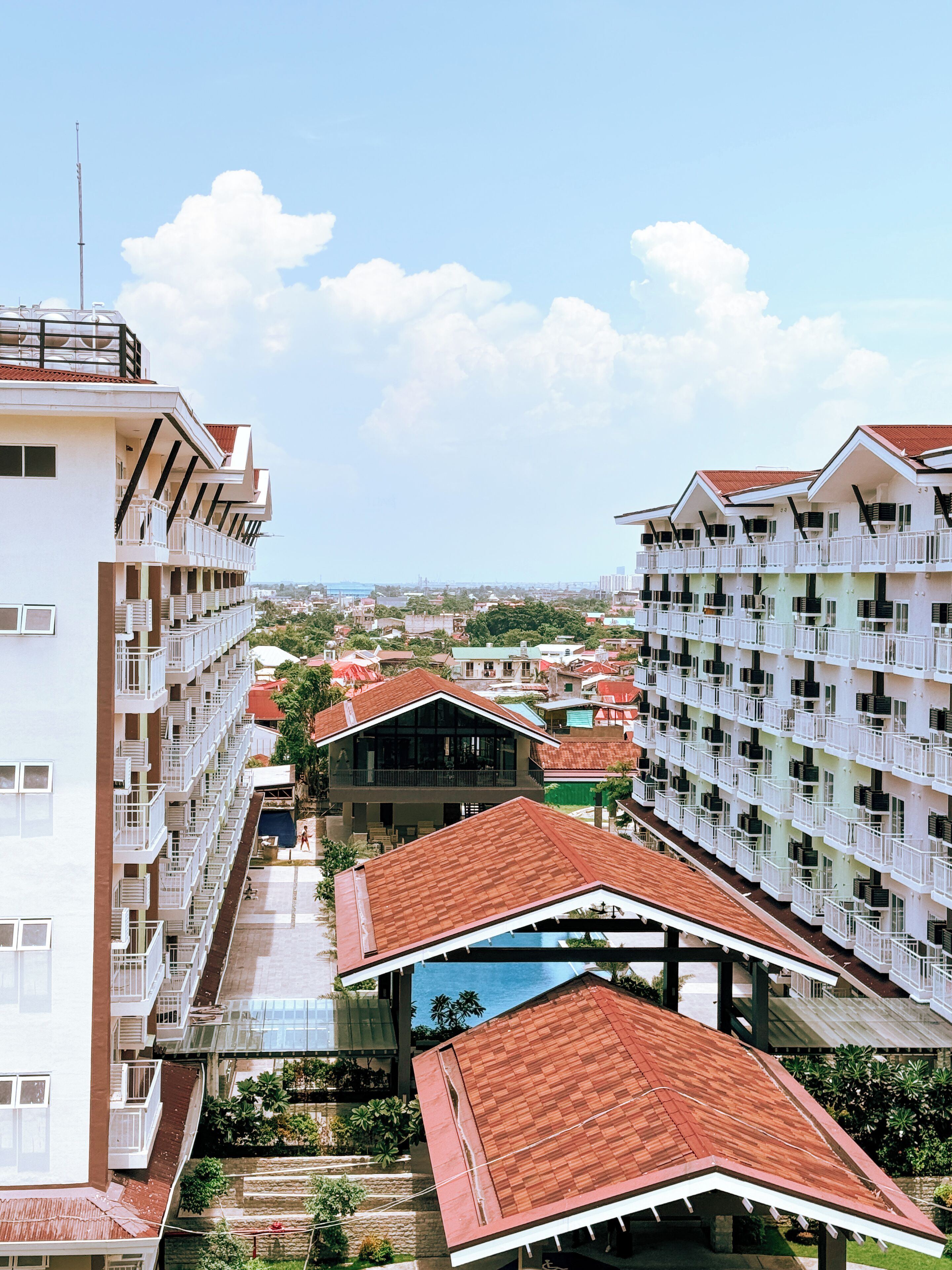 A high-rise hotel with multiple balconies, a swimming pool, and a view of the surrounding cityscape.