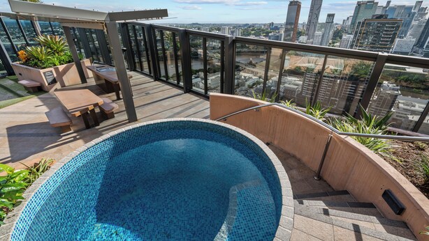 A rooftop pool with a city view, outdoor seating, and a pergola. - 3-Bed City View Apt with Free Parking (South Brisbane)