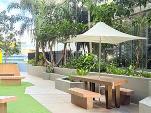 An outdoor seating area with a table and benches, surrounded by planters and greenery.