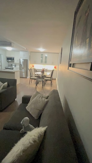 A living room with a sofa, a dining table with chairs, and a kitchen in the background. - Charming 2-bedroom apartment in terrific Burlington with WiFi and free parking (Burlington)