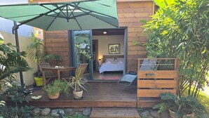 A wooden cabin with a deck, outdoor seating, and potted plants.