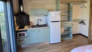 A compact kitchen with a microwave, stove, sink, and white refrigerator.