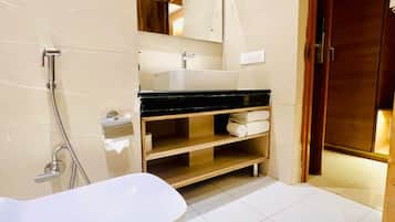 A modern bathroom with a freestanding bathtub, a mirror above the sink, and a wooden door.