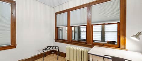 A room with a wooden floor, a white radiator, a desk, and a chair.