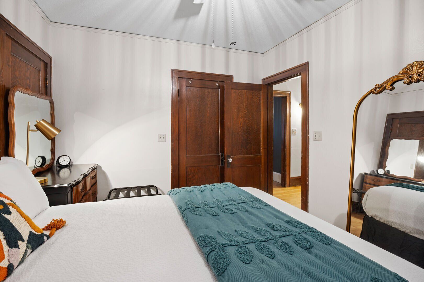 Een hotelkamer met een groot bed, een bureau met lamp, een kledingkast en een spiegel.