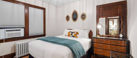 Een slaapkamer met een bed, een dressoir, een spiegel en een radiator.