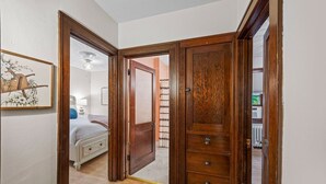 Une chambre à coucher comprenant un lit, une table de chevet, une commode et une porte donnant sur une autre pièce.