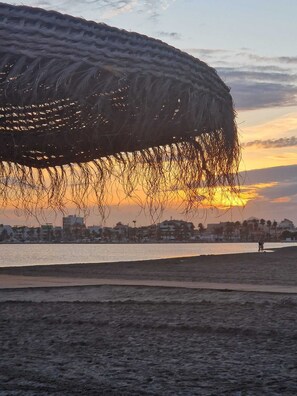 Ein Strand mit einer großen, gebogenen Struktur im Vordergrund.
