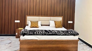 Une chambre avec un mur recouvert de panneaux de bois, un lit avec une literie à motifs, une table de chevet et un ventilateur de plafond.
